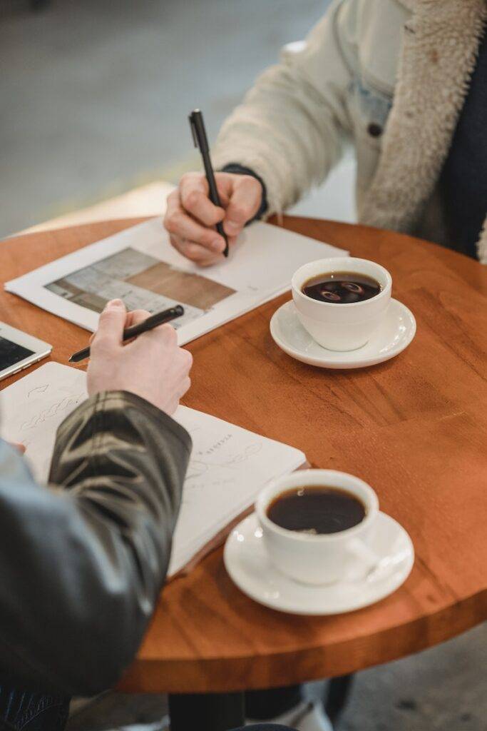 Preciso me defender em um processo 3 Businessmen signing contract table with coffee